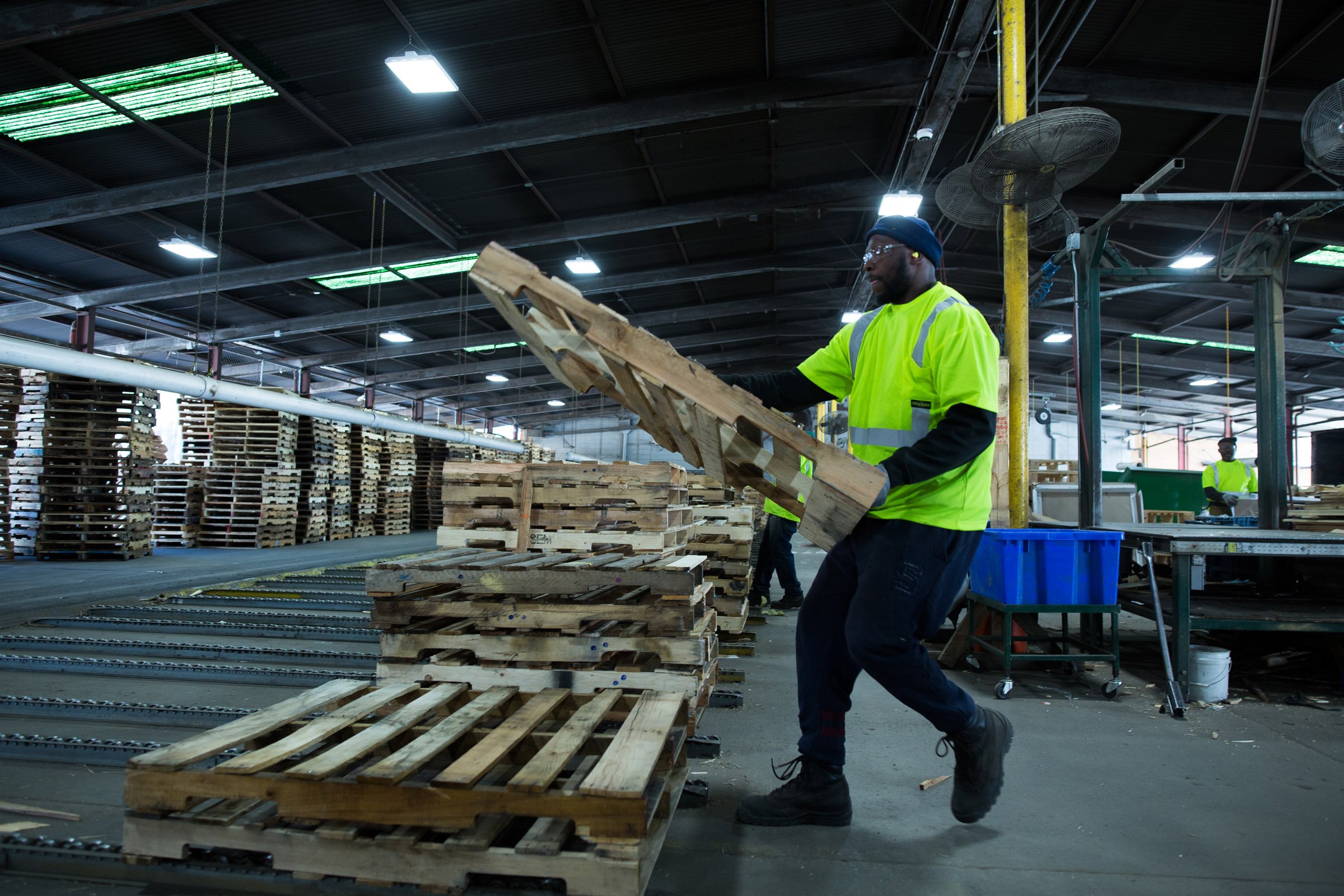 A man placing a pallet on a stack of pallets